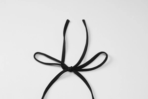Detail shot of a black halter tie-up drawstring knot on a slim fit solid dress