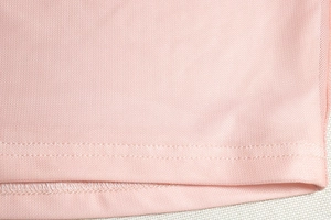 Close-up of pink mesh fabric showing precise double-needle stitching on the garment hem