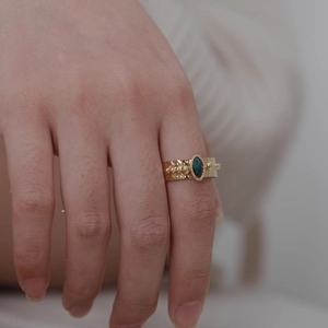 Detailed view of 18K gold-plated hammered ring with an oval dark green gemstone inlay