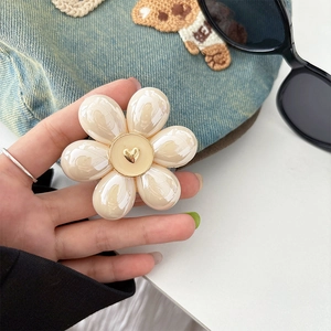 Close-up of a pearlescent cream flower phone grip with a golden 3D heart center detail