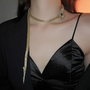Detail of gold snake necklace with green gemstone eyes and sparkling crystal embellishments