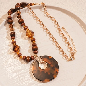 Détail du collier de perles avec pendentif écaille de tortue et fermoir doré