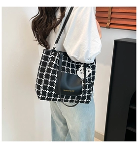 Fashionable black and white tweed tote bag with cat charm shown on model in home setting