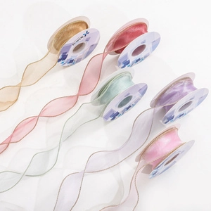 Macro detail of wavy edge snow yarn ribbons with gold trim in various elegant pastel colors