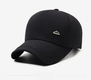 Detail of dark black baseball cap featuring a metal mountain badge and side embroidery