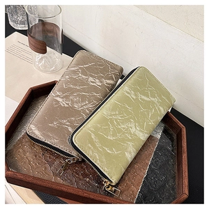 Detail of long velvet-texture wallets in tan and light green on a wooden tray