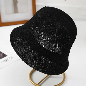 Chic black hollow crochet bucket hat with bow detail on a stylish display stand