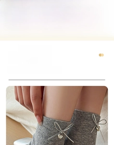 Détail de chaussettes mi-mollet grises avec nœud argenté et pendentif cœur style ballet