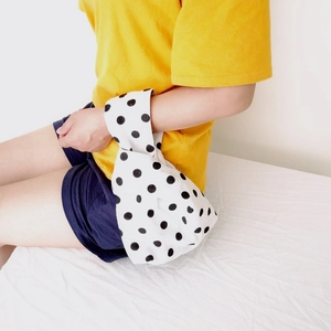 Polka dot canvas wrist bag with unique cross-handle design shown on model's wrist