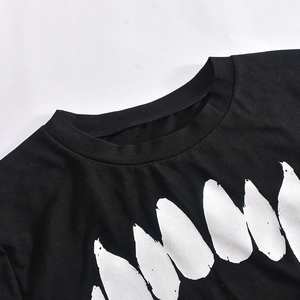 Détail du t-shirt noir à col rond avec un imprimé graphique de dents blanches stylisées