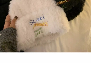 Detailed view of plush white faux fur knit hat texture with colorful embroidery accents