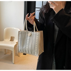 Vertical striped linen tote bag with decorative button and woven handle detail