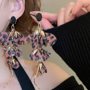 Detail of pink leopard print fabric petal earrings with gold tassels on a model