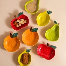 Flat lay of colorful fruit-shaped ceramic bowls including lemon, apple, and pear designs