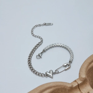 Detail of silver stainless steel link bracelet with heart and safety pin pendants