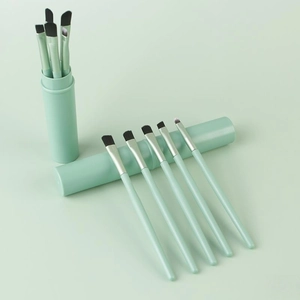 Pale green 12-piece makeup brush set with storage tube on matching soft background