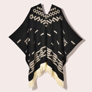 Flat lay of black western poncho with beige geometric patterns and fringe details