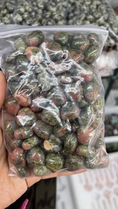 Close-up of bulk polished Unakite heart stones packed in a clear plastic zipper bag