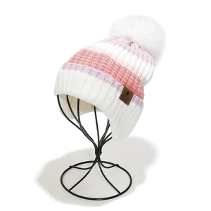 Detail of colorful striped knit beanie with white pom-pom and leather logo patch