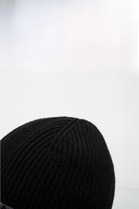 Close-up of thick black ribbed knit beanie showing dense winter warmth fabric detail