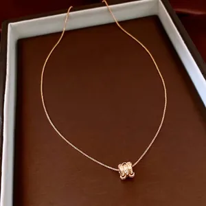 Elegant 18k gold plated necklace with H-shaped crystal pendant on a leather tray