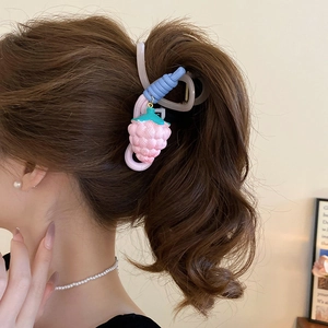 Detail of translucent hair claw clip with blue braided rope and pink strawberry charm
