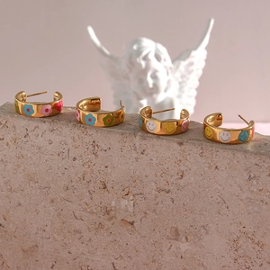 Close-up of golden stainless steel hoop earrings with colorful enamel flower and smiley face