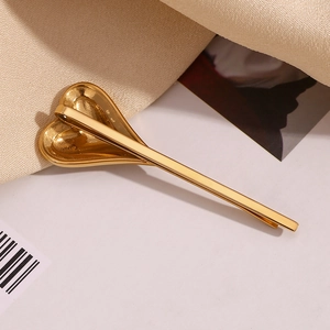 Detail of 18K gold-plated heart hair clip with pavé rhinestones on textured fabric