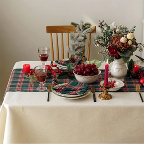 Festive red and green plaid table runner set with elegant holiday dining arrangement