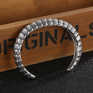 Detail showing silver dragon scale texture of the punk style steel cuff on a dark surface