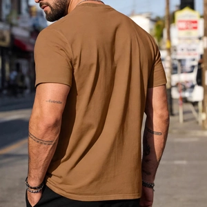 Men's casual brown crew neck cotton t-shirt shown from a rear side urban lifestyle view