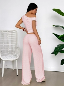 Detail showing pink pleated texture of the one-shoulder top and wide-leg trousers set