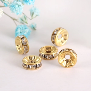 Detailed view of five golden crystal spacers with clear rhinestones for DIY jewelry making