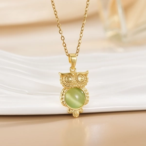 Macro detail of golden owl pendant featuring a centered green cat-eye gemstone