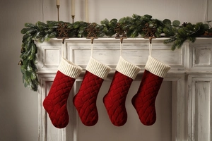 Close-up of four red knitted Christmas stockings hanging on a festive white fireplace