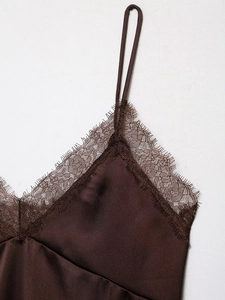 Détail du décolleté en dentelle et du tissu en satin marron brillant du haut