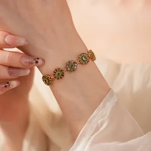 Detailed close-up of a gold floral bracelet with green pear-cut stones and dark accents