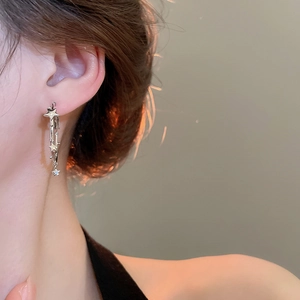 Close-up of silver star earrings with long tassels on female model profile view