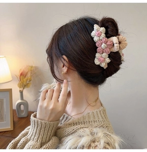 Detail of hand-crocheted floral hair claw clip in soft pink and beige wool yarn