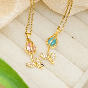 Gold tulip pendant necklace set with pink and teal opal stones on satin background