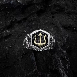 Vintage silver Poseidon trident ring with gold accent on a dark stone background