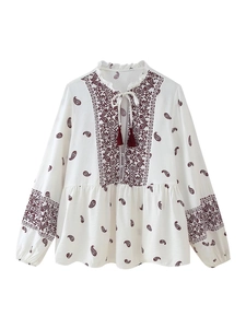 Details einer böhmischen weißen Bluse mit Paisley-Muster und Quasten am Ausschnitt