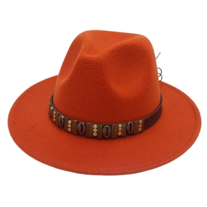 Detail of burnt orange felt fedora featuring leather band and metallic shell ornaments