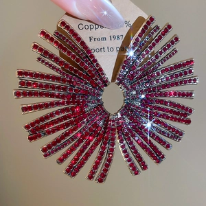 Macro shot of silver fan-shaped earrings with vibrant red rhinestones on a display card