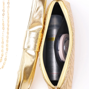 Interior view of gold metallic handbag showing capacity for cosmetics and chain strap