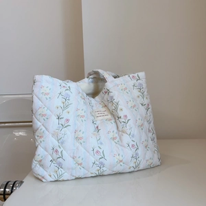 Macro detail of French floral quilted cotton fabric and woven label on shoulder bag
