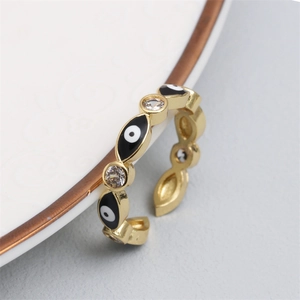 Macro detail of adjustable gold evil eye ring with black enamel and zircon accents