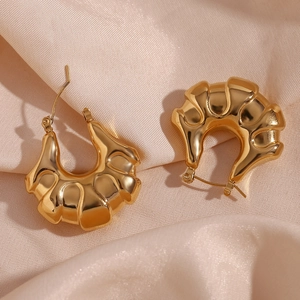 Detailed close-up of 18K gold plated hollow earrings with textured surface on satin