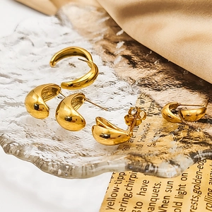 Close-up of 18K gold teardrop earrings displayed on silk and vintage paper texture