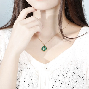 Close-up of gold Taurus zodiac necklace with green texture and crystal inlay on model